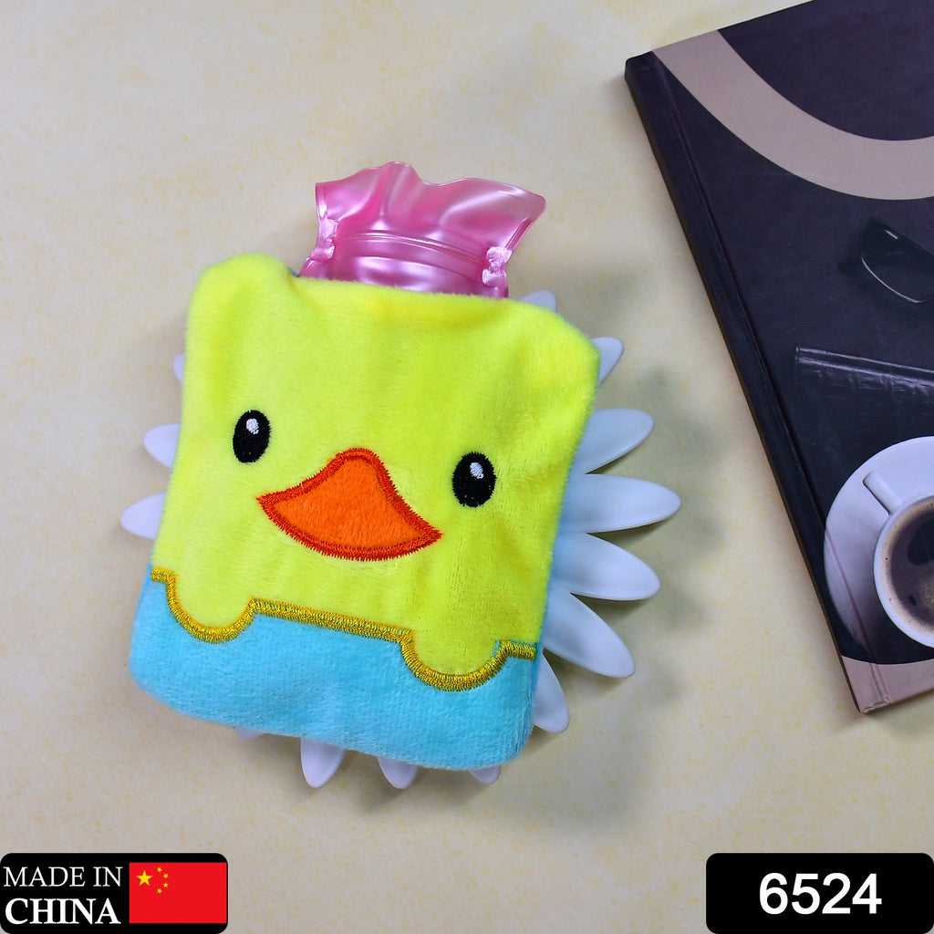 A yellow duck hot water bag sits on a light brown surface next to a dark book.