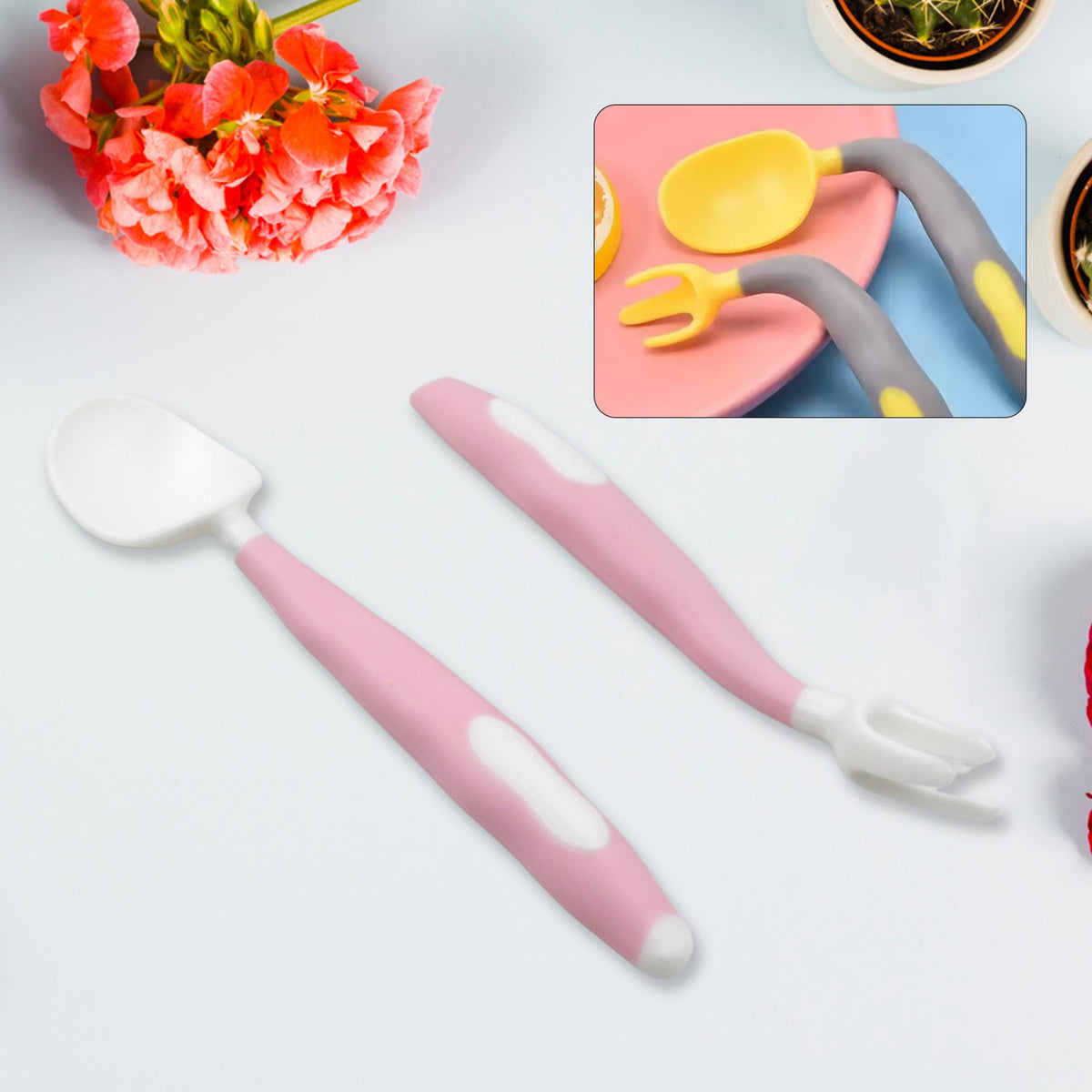 A pink and white baby spoon and fork set with a floral background and an inset of a yellow and grey set.