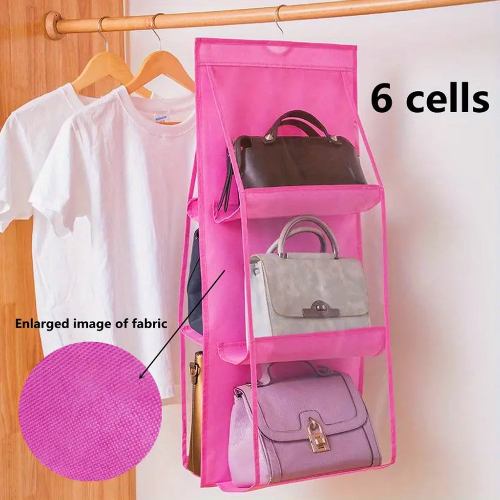 A pink 6-cell hanging organizer with purses hangs in a closet with white t-shirts and a fabric swatch.