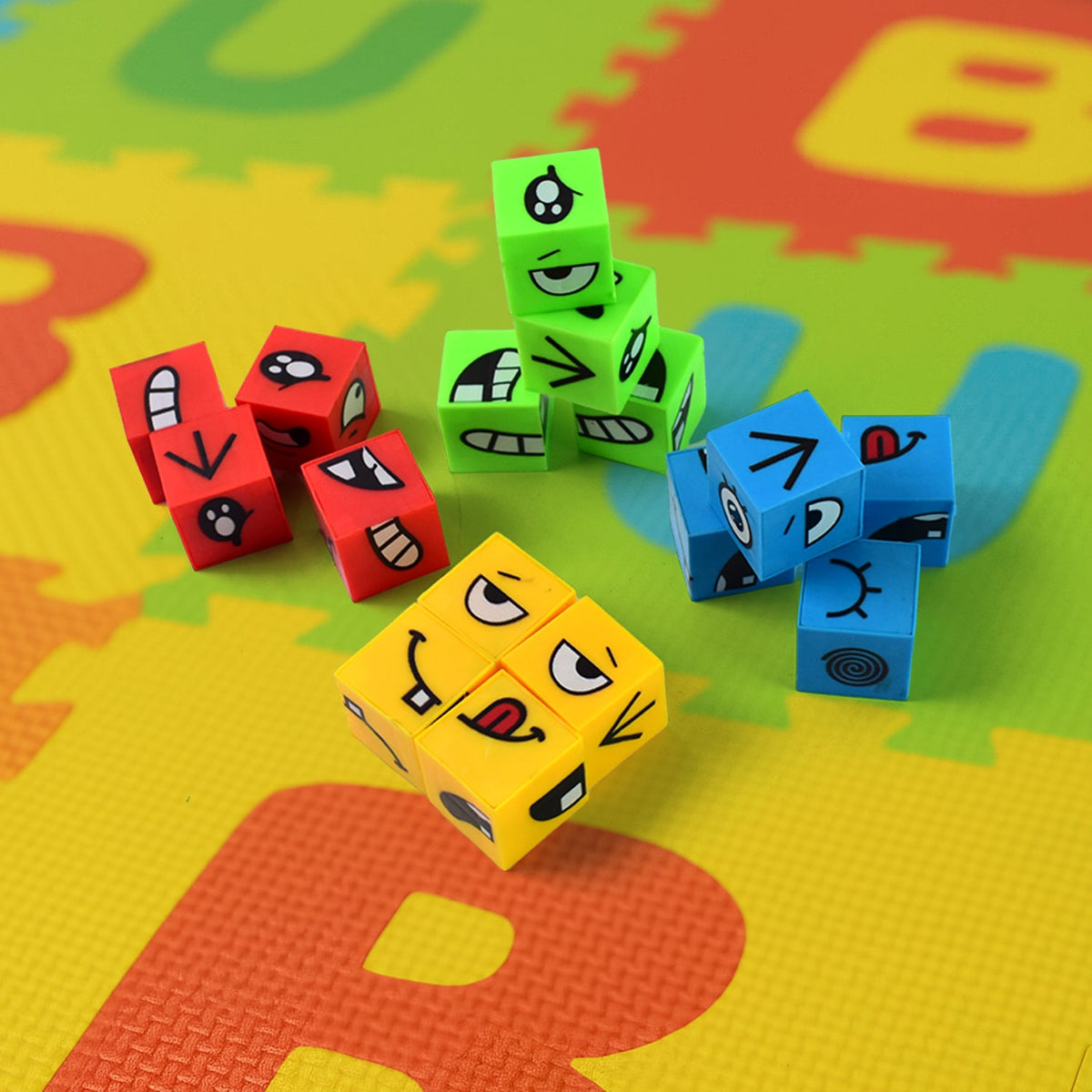 Colorful emotion cubes in blue, red, green, and yellow are scattered across a vibrant, multi-colored foam play mat.