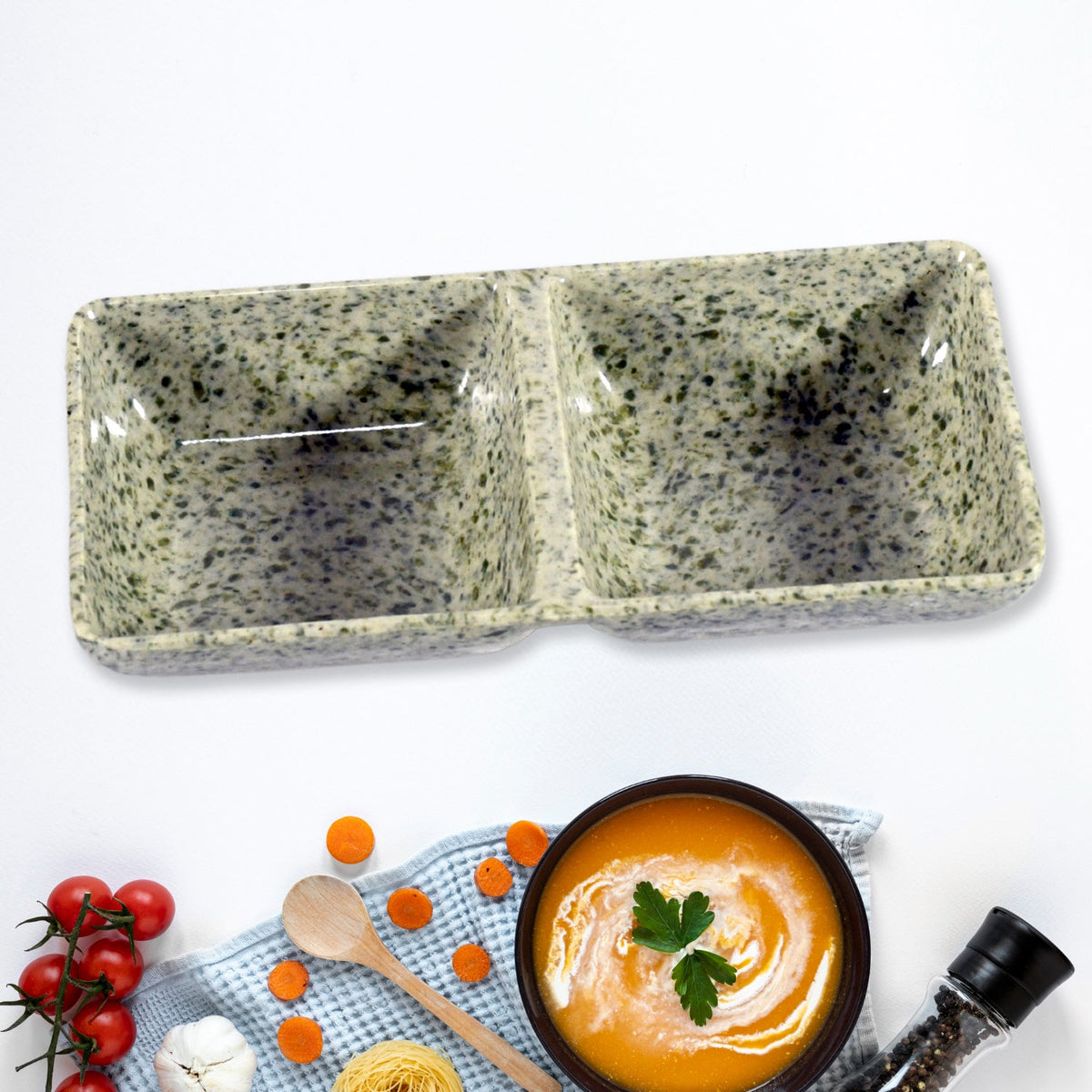 A speckled gray-green ceramic two-compartment serving dish on a white surface with food items.