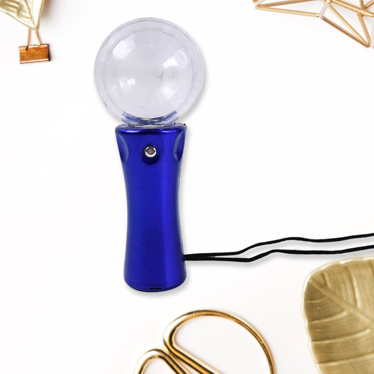 Blue disco ball light wand with a black lanyard, surrounded by gold office supplies on a white desk.