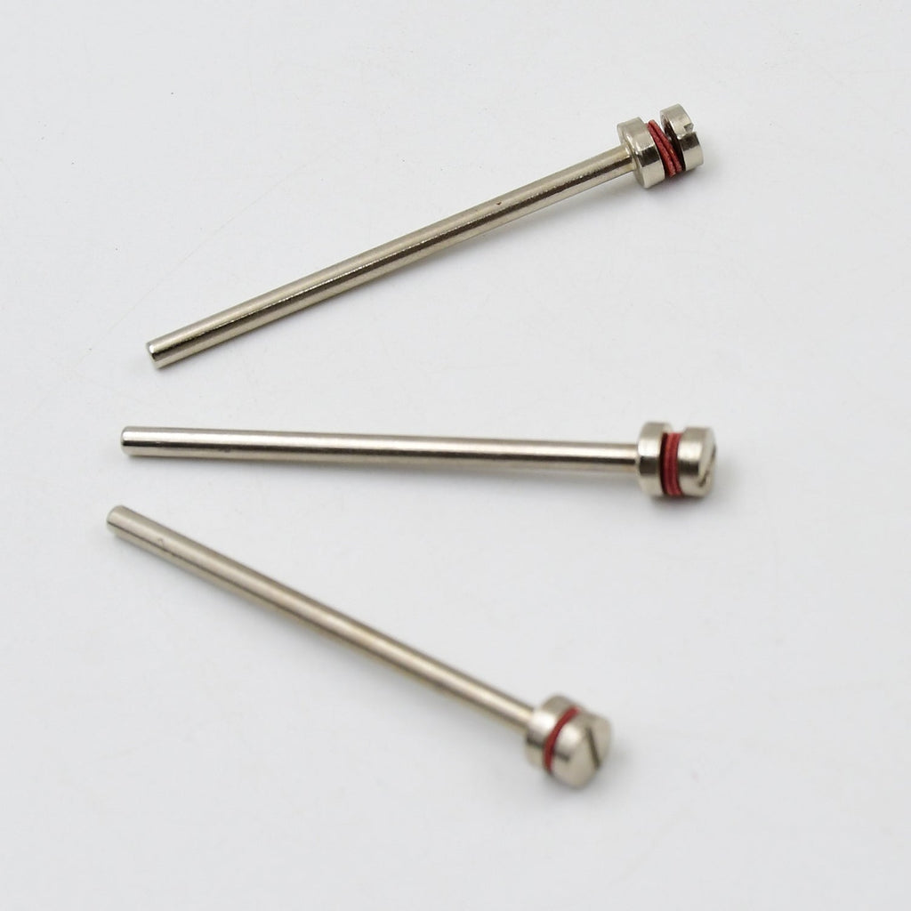 Three silver mandrels with red bands and screw heads lie scattered on a plain white background.