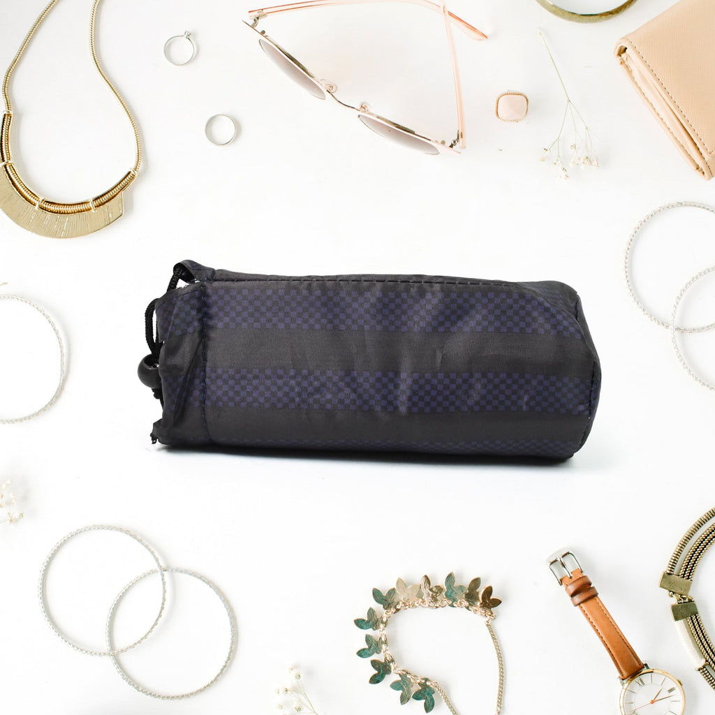 A navy blue drawstring pouch with vertical stripes lies flat on a white surface, surrounded by various pieces of jewelry and