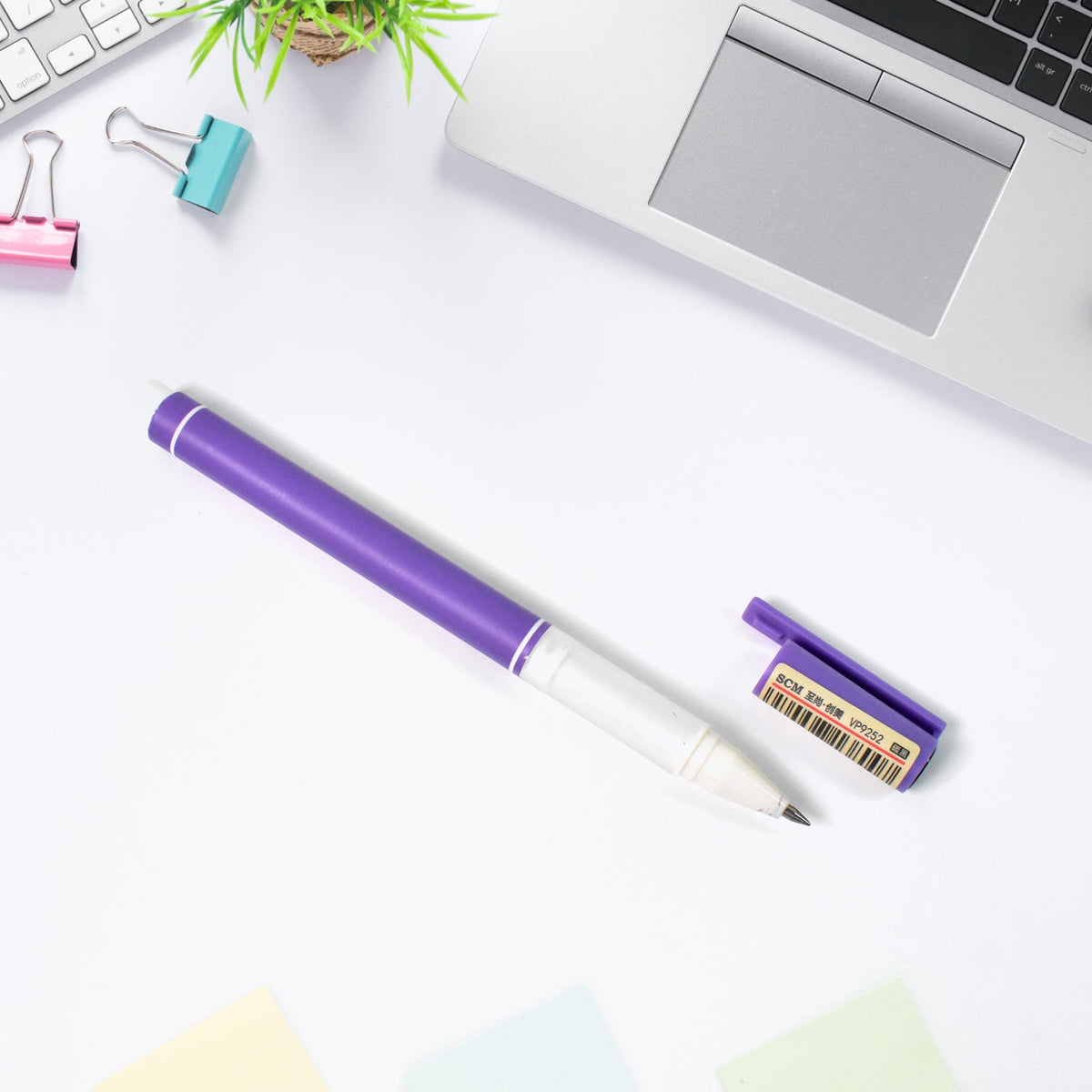 A purple gel pen with its cap removed and barcode sticker visible, rests on a white desk.