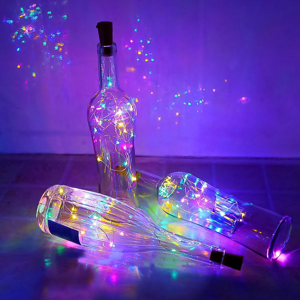 Three clear bottles with multi-color LED string lights inside, one standing and two lying down, against a purple background.