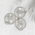 Three transparent suction cup hooks are arranged on a white textured surface with a subtle shadow.