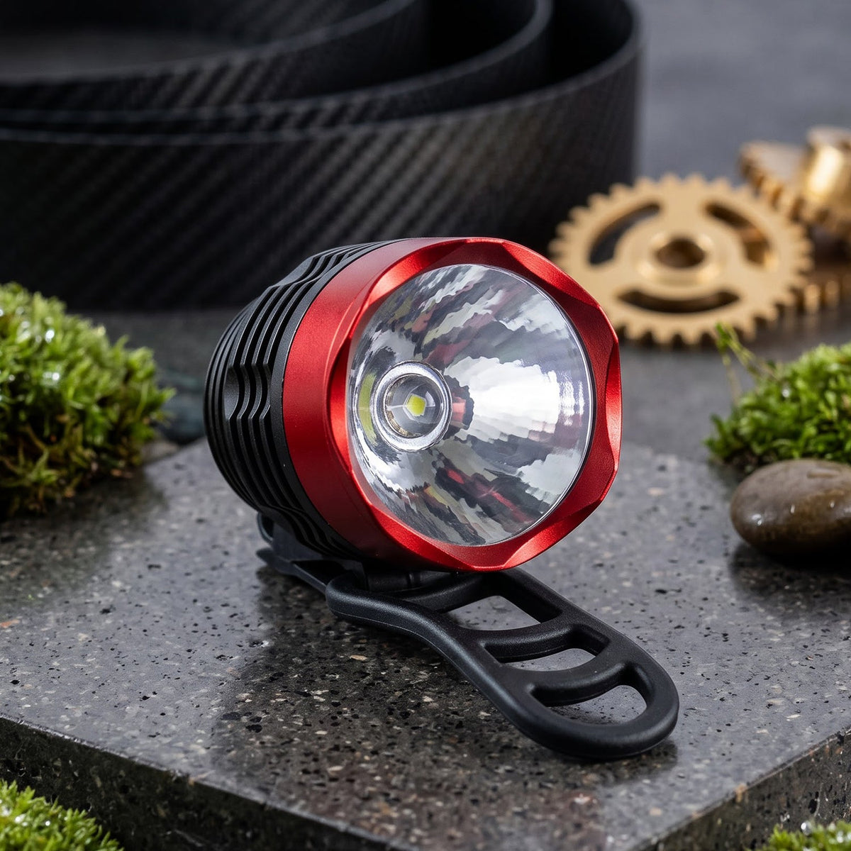 A close-up of the red and black bicycle headlight with a silver reflector, resting on a stone surface with moss.