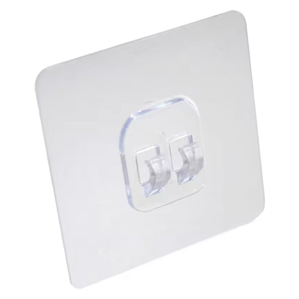 A clear square self-adhesive wall hook with two transparent prongs is shown against a plain white background.