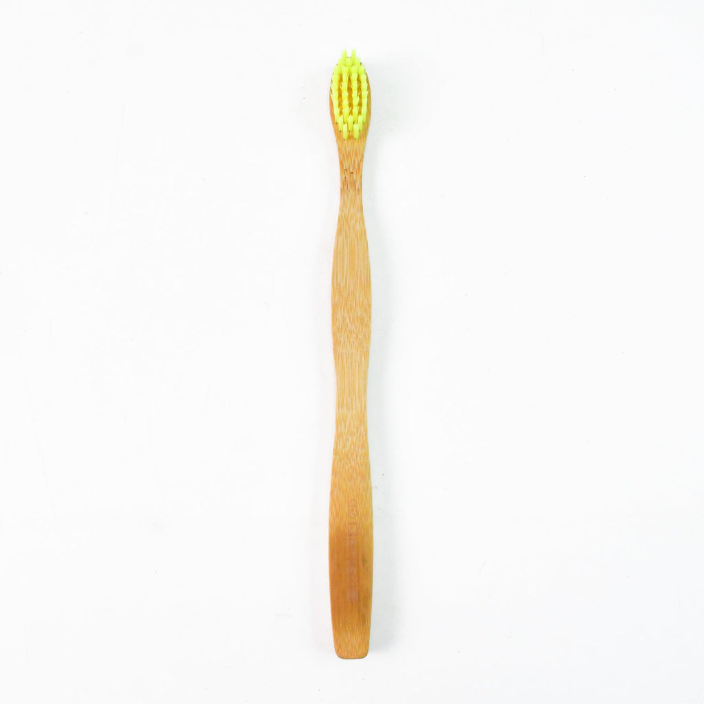 A single bamboo toothbrush with yellow bristles stands upright on a plain white background.