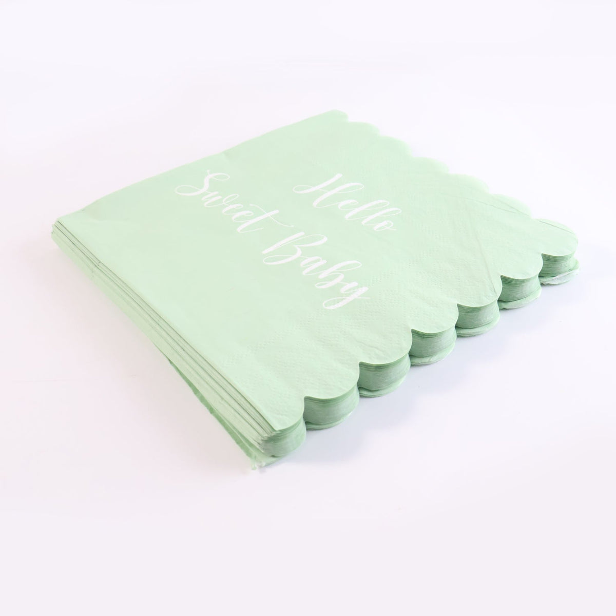 A stack of mint green scalloped napkins with "Hello Sweet Baby" in white script, isolated on a white background.