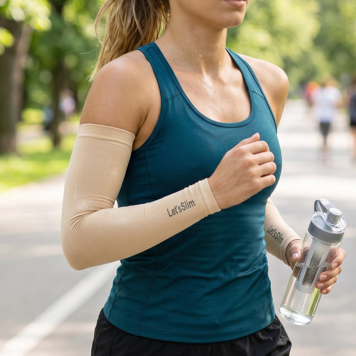 A woman running outdoors, wearing beige arm sleeves with "Let's Slim" logo, holding a water bottle.