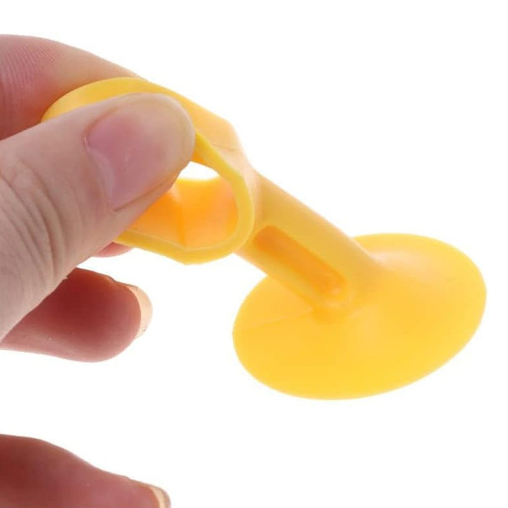 A hand holds a yellow silicone suction cup door stopper, showing its flexible material and design.