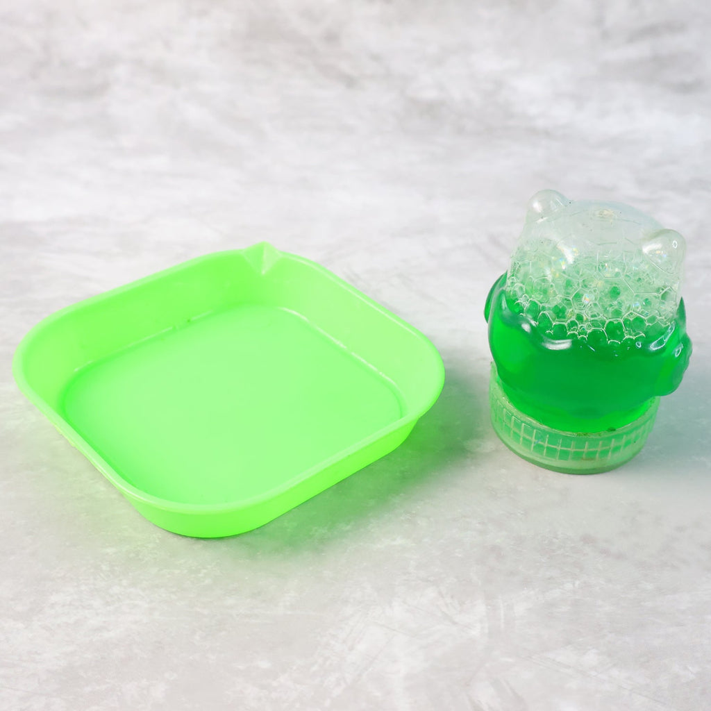 A bright green square tray filled with bubble solution sits next to a small green bottle of bubble solution.