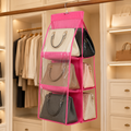 A pink hanging purse organizer with clear pockets holds various handbags in a well-lit closet.