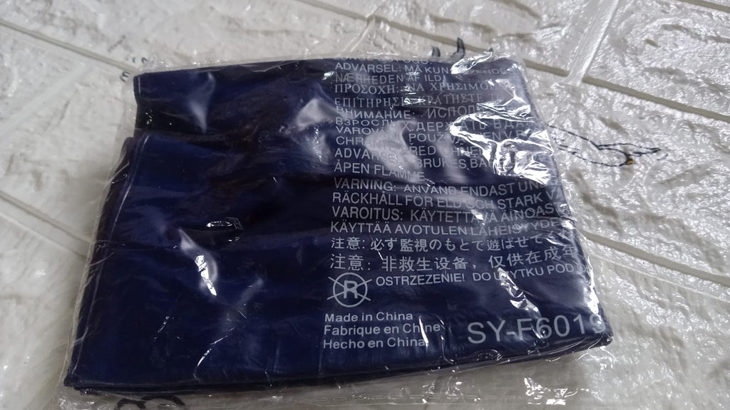 A blue inflatable pillow is sealed in clear plastic packaging, displaying product information and warnings.