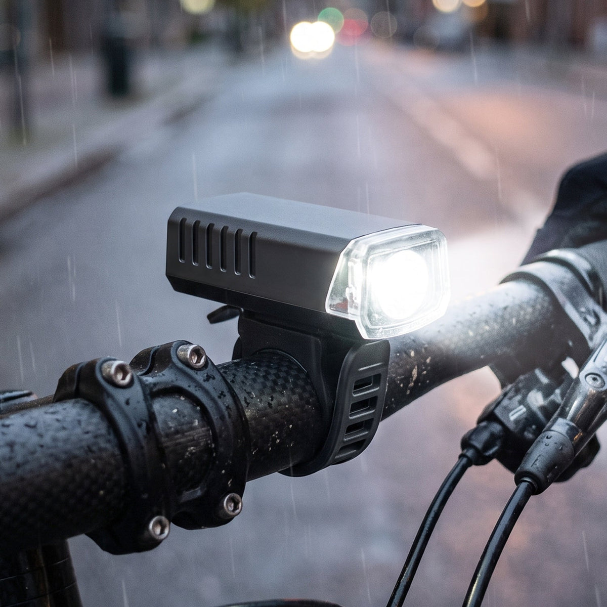Black rectangular bicycle headlight with a clear lens, mounted on handlebars, shining brightly in the rain 