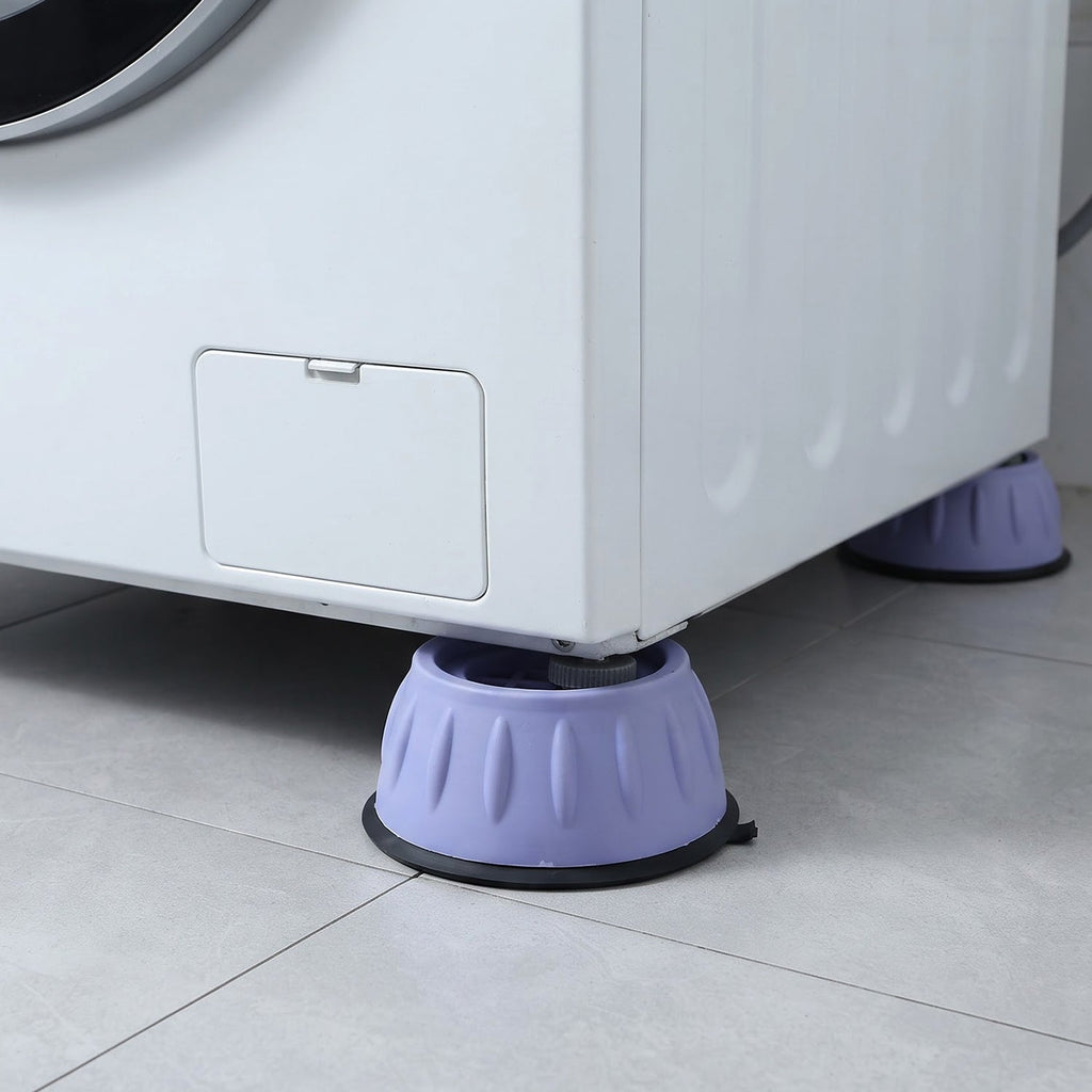 Two purple anti-vibration pads supporting the front and back corners of a white washing machine on a tiled floor.