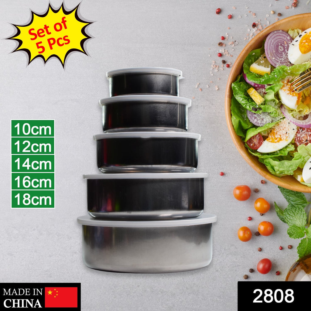 A set of five stacked stainless steel food containers with clear lids, showing size labels and a salad bowl in the