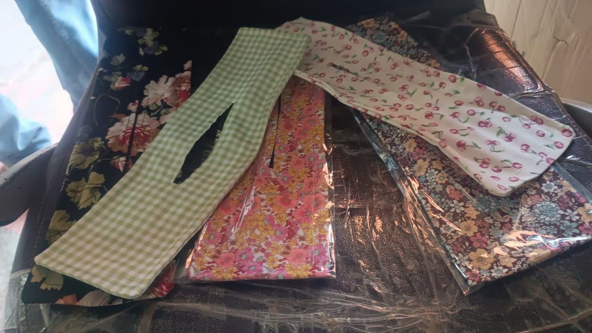 Multiple floral and checkered patterned hair bun makers, some in packaging, on a dark surface.