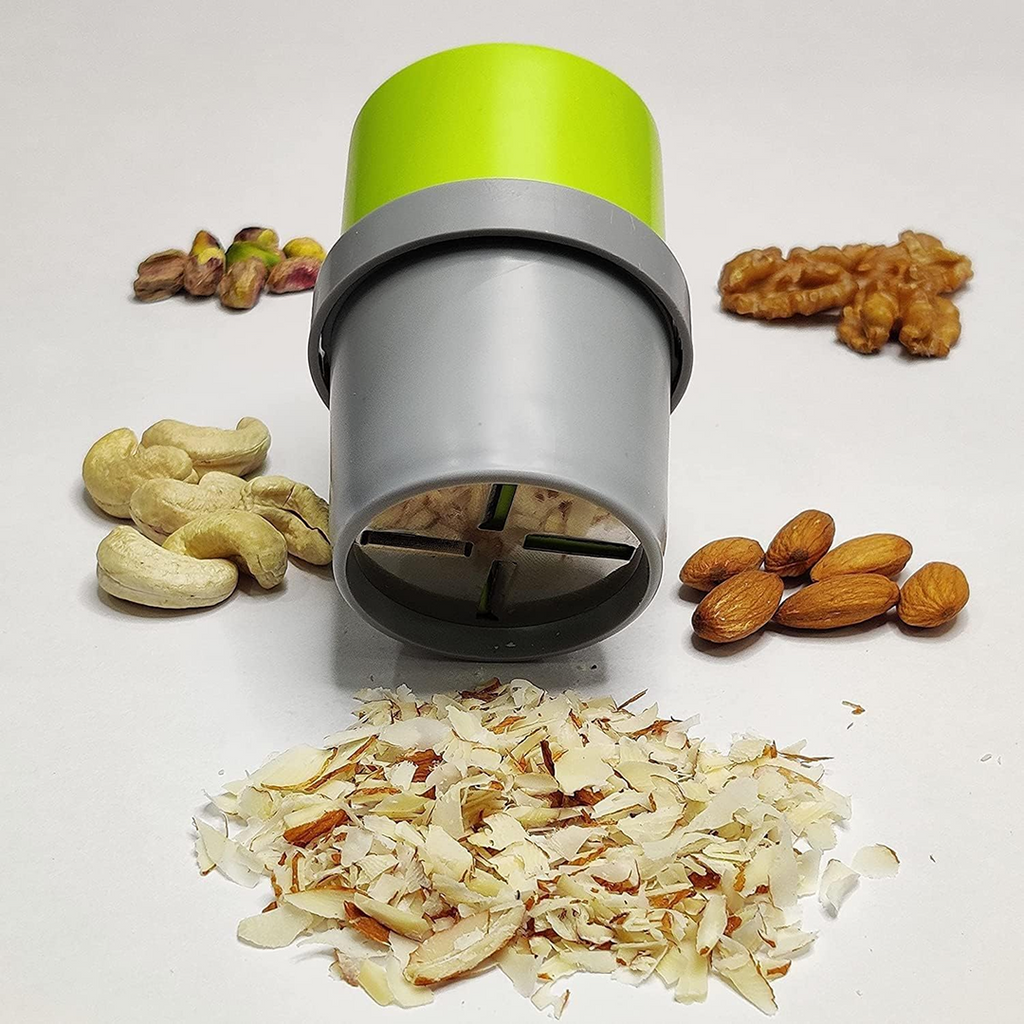A green and gray dry fruit slicer stands upright, surrounded by whole nuts and a pile of sliced almonds.