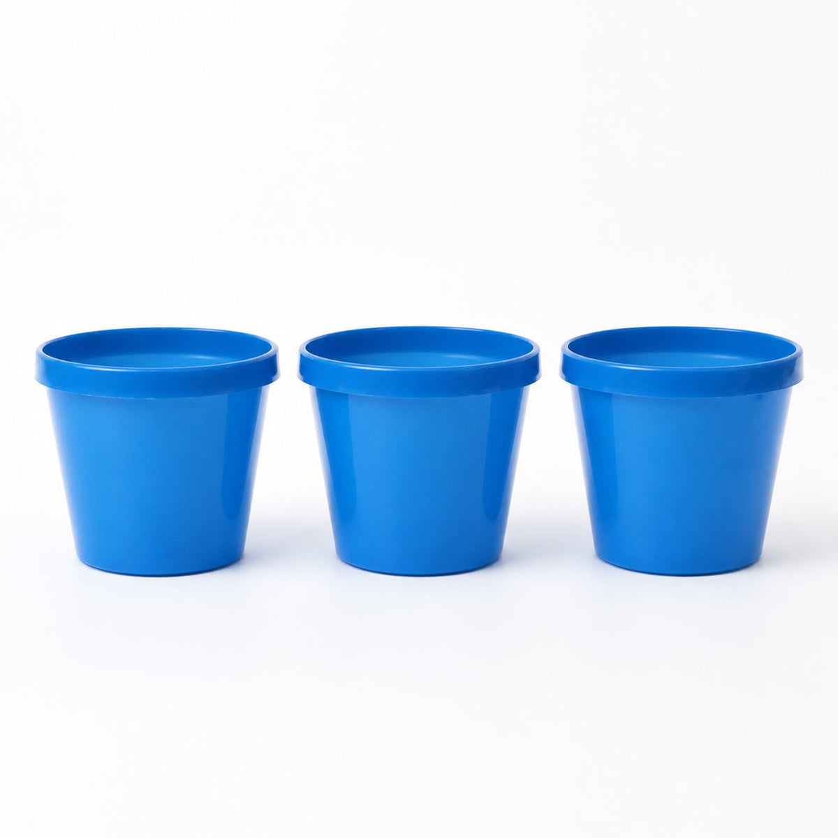 Three empty blue plastic planter pots are arranged in a row on a white background.