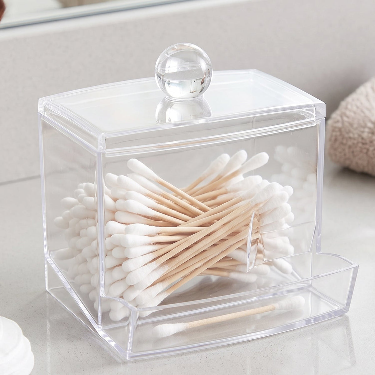 Clear acrylic cotton swab dispenser filled with cotton swabs, with a small inset image.