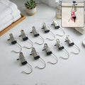 Ten metal clip hangers with black rubber tips are neatly arranged on a white marble countertop next to folded towels