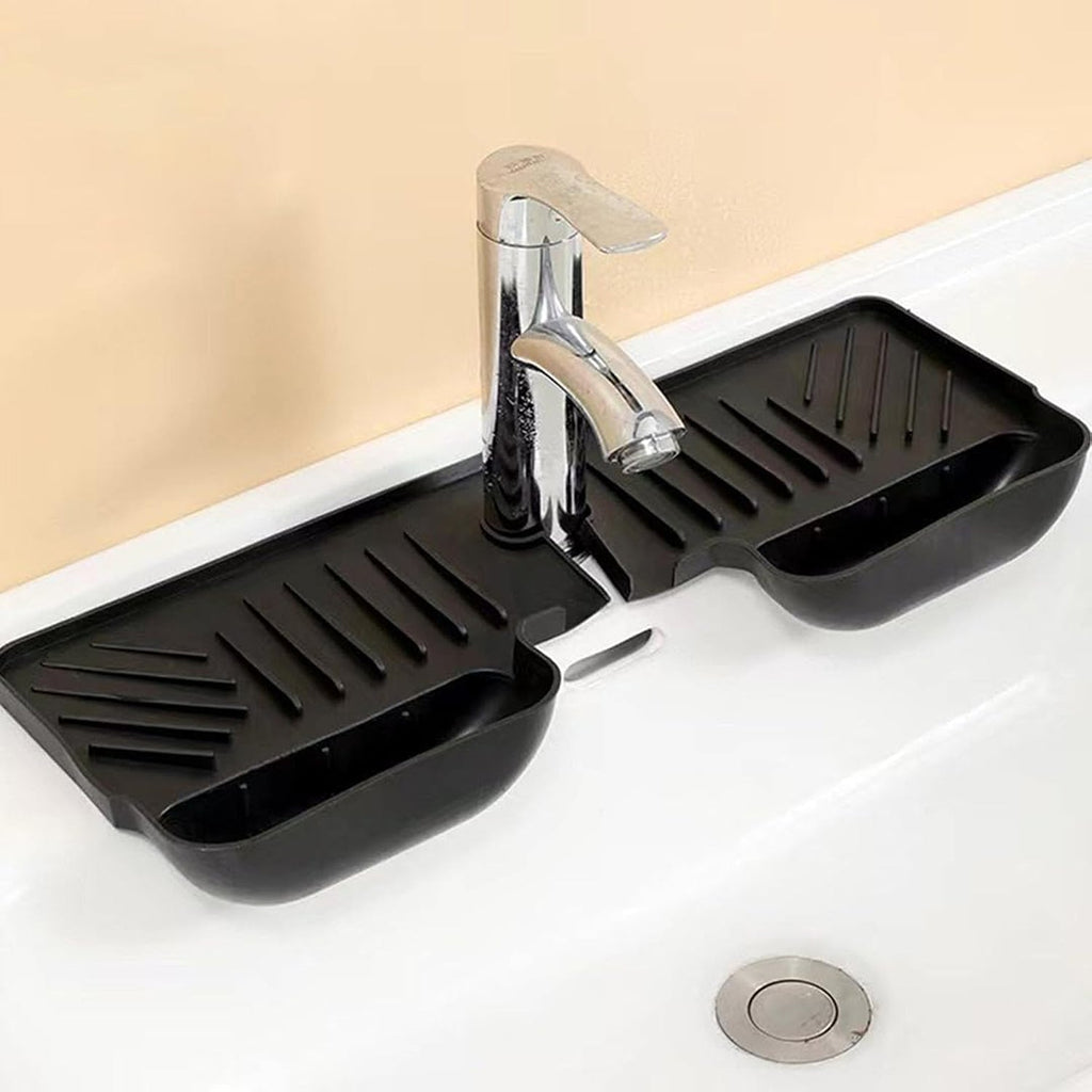 A black silicone faucet splash guard with drainage grooves and two side compartments, installed around a chrome faucet in a