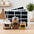 Three glass jars with chalkboard labels for rice, cookies, and macaroni, with blank labels and a white marker.