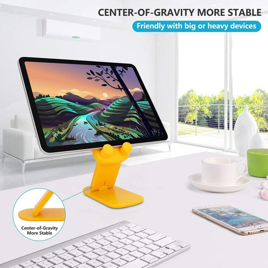A yellow cartoon duck stand holds a tablet displaying a landscape, with a keyboard and phone on a white desk.