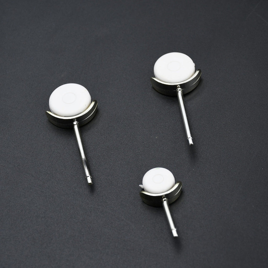 Three small white and silver wheels, designed to attach to the airplane fan, are arranged on a dark surface.