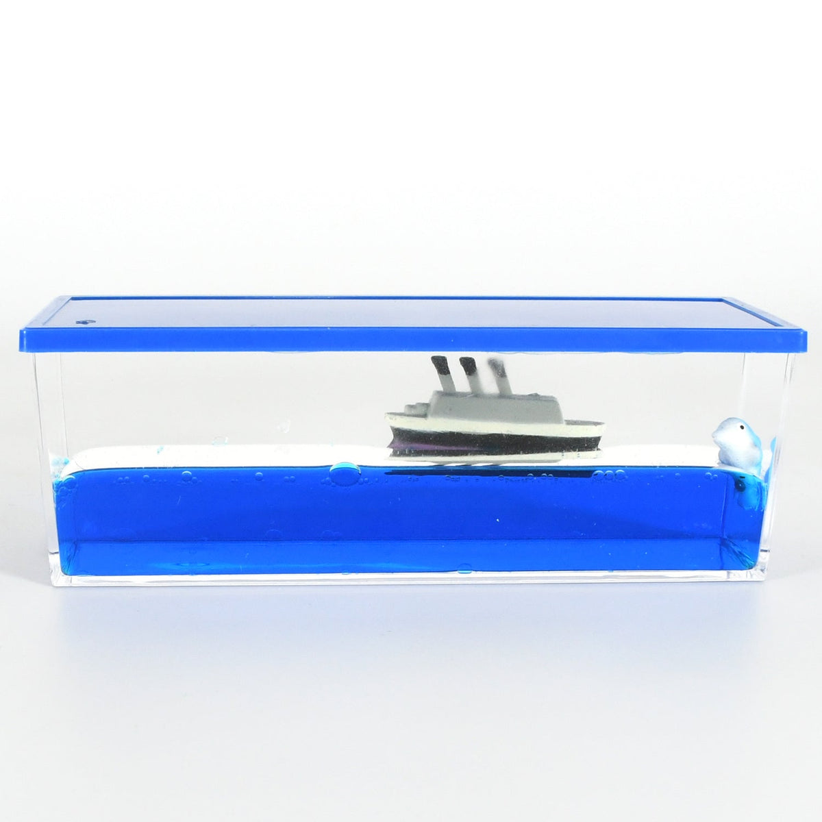 A clear rectangular acrylic box with blue liquid, a white and gray ship, and a small white dolphin inside, set against a