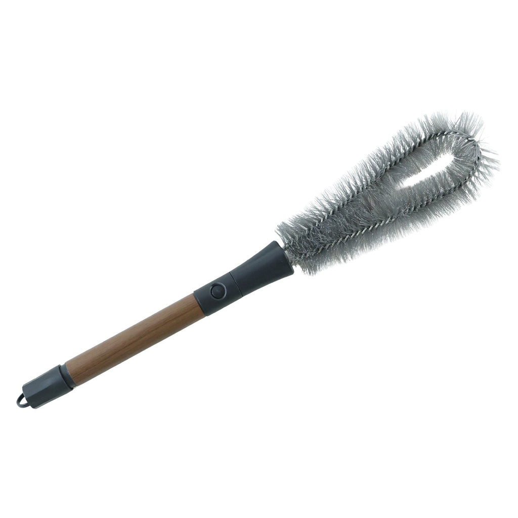 A grey and brown cleaning brush with a flexible head is positioned diagonally on a plain white background.