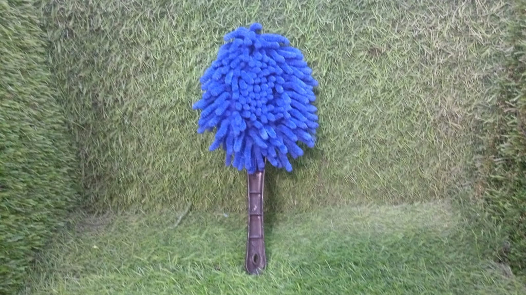 Blue microfiber duster with a black handle standing upright on a green artificial grass background.