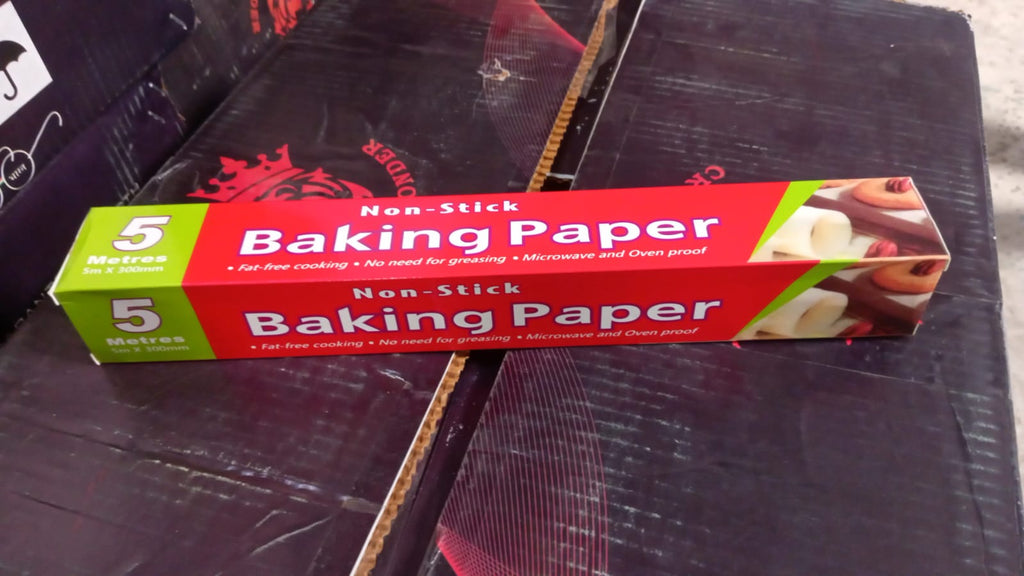 A red and green box of non-stick baking paper resting on a dark, patterned surface.