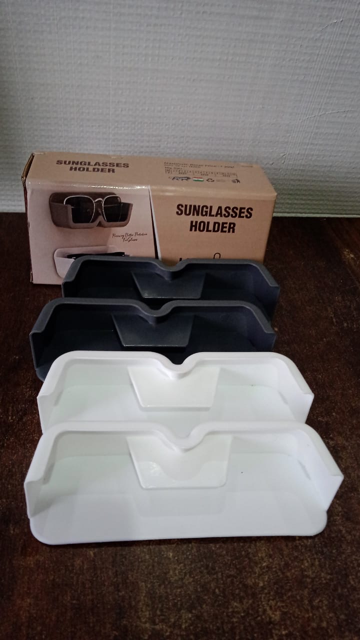 Two black and two white glasses holders stacked on a wooden surface, with two brown boxes in the background.