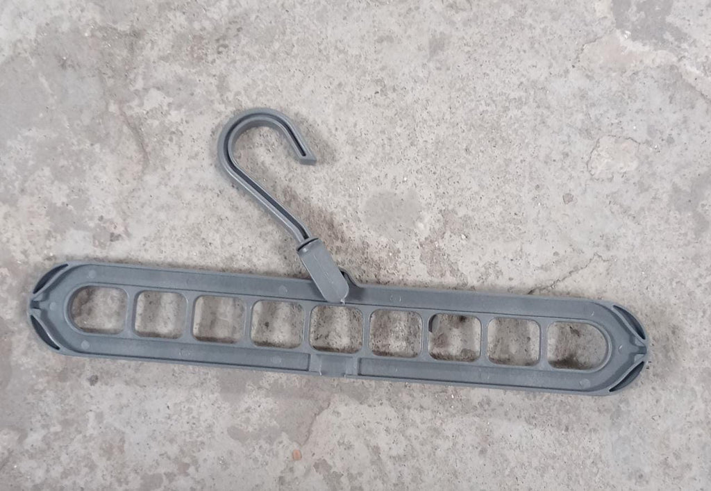 A gray plastic multi-port hanger with a rotating hook rests on a textured concrete surface.