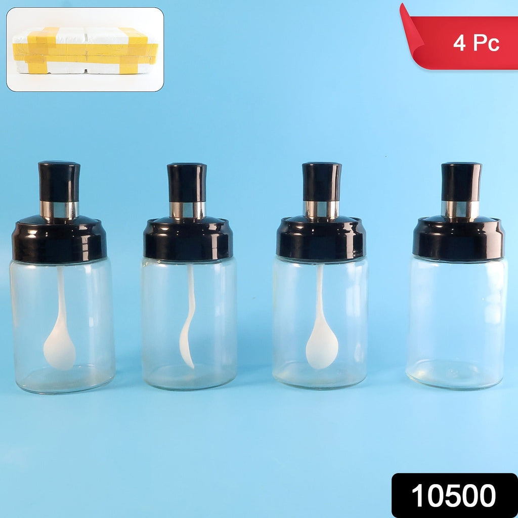 Four transparent spice jars with black lids and white spoons on a blue background.