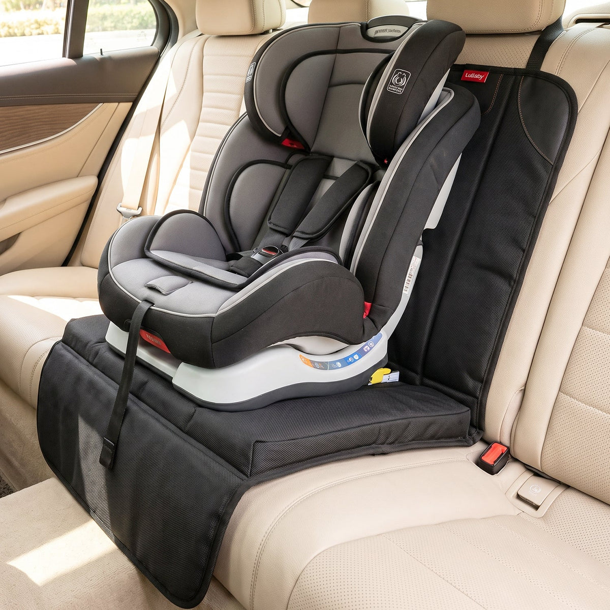 A gray and black child's car seat is secured on a black protector covering a beige vehicle seat.