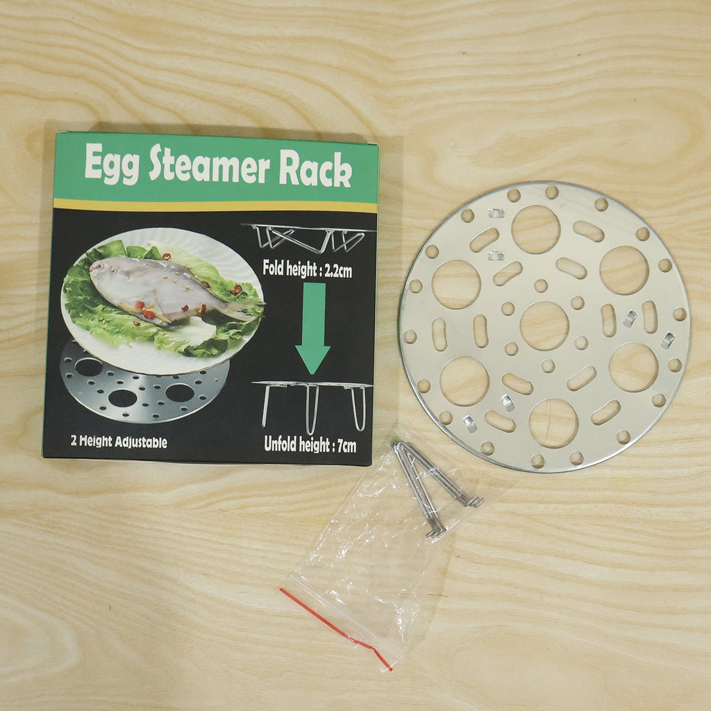 An egg steamer rack and its components, including a small bag of legs, are laid out next to its product box on a wooden