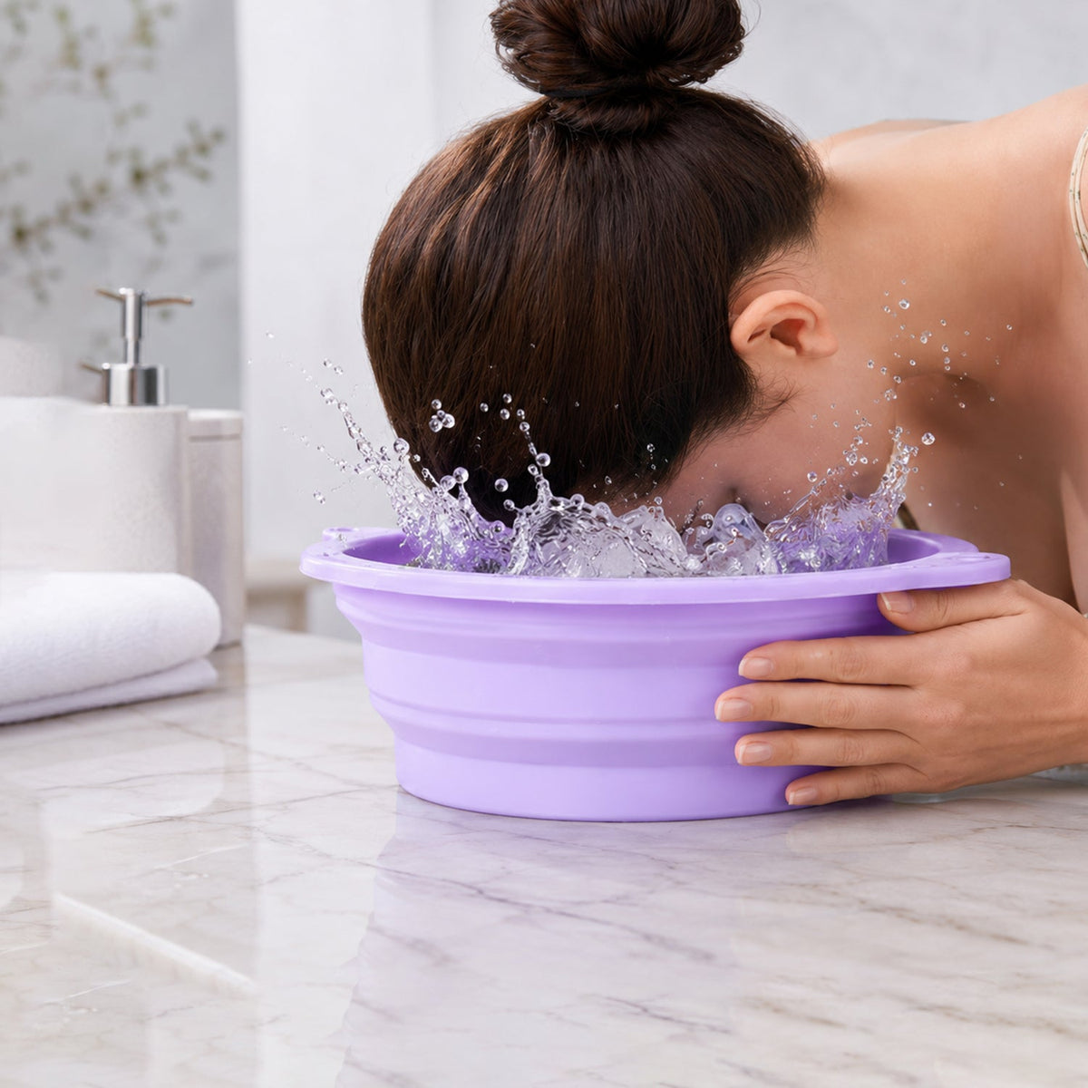 A woman splashes her face in a purple collapsible silicone bowl filled with water and ice cubes on a marble counter. – view 8