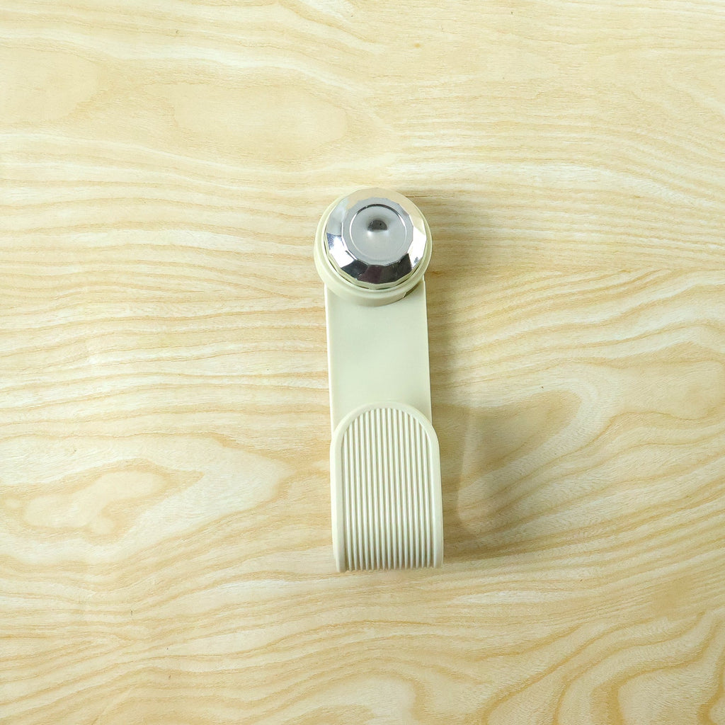 A cream-colored hook with a chrome top and ribbed texture is presented on a light wood grain surface.