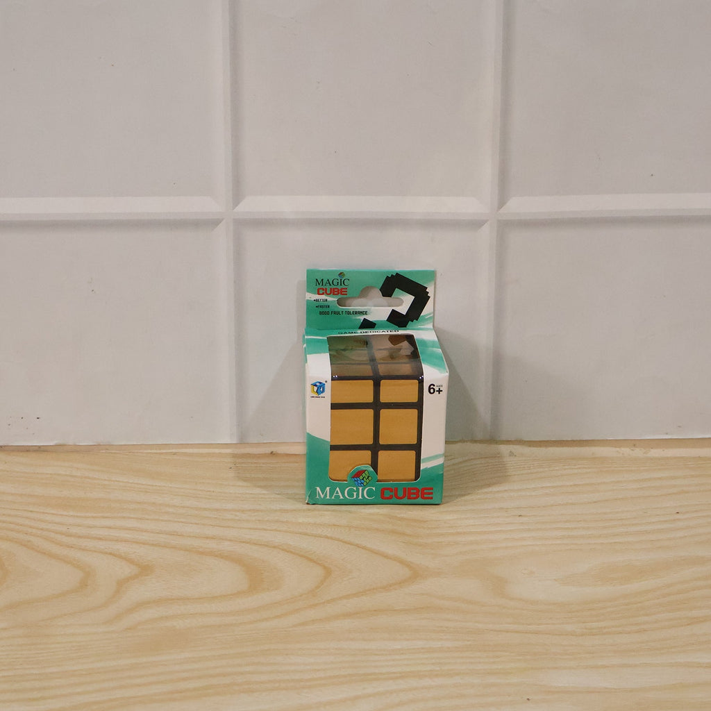 A small green and white package for a "Magic Cube" with a gold mirror cube pictured on it, sits on a wooden surface against