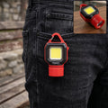 Red and black mini LED flashlight with a carabiner clip attached to a black jeans pocket.