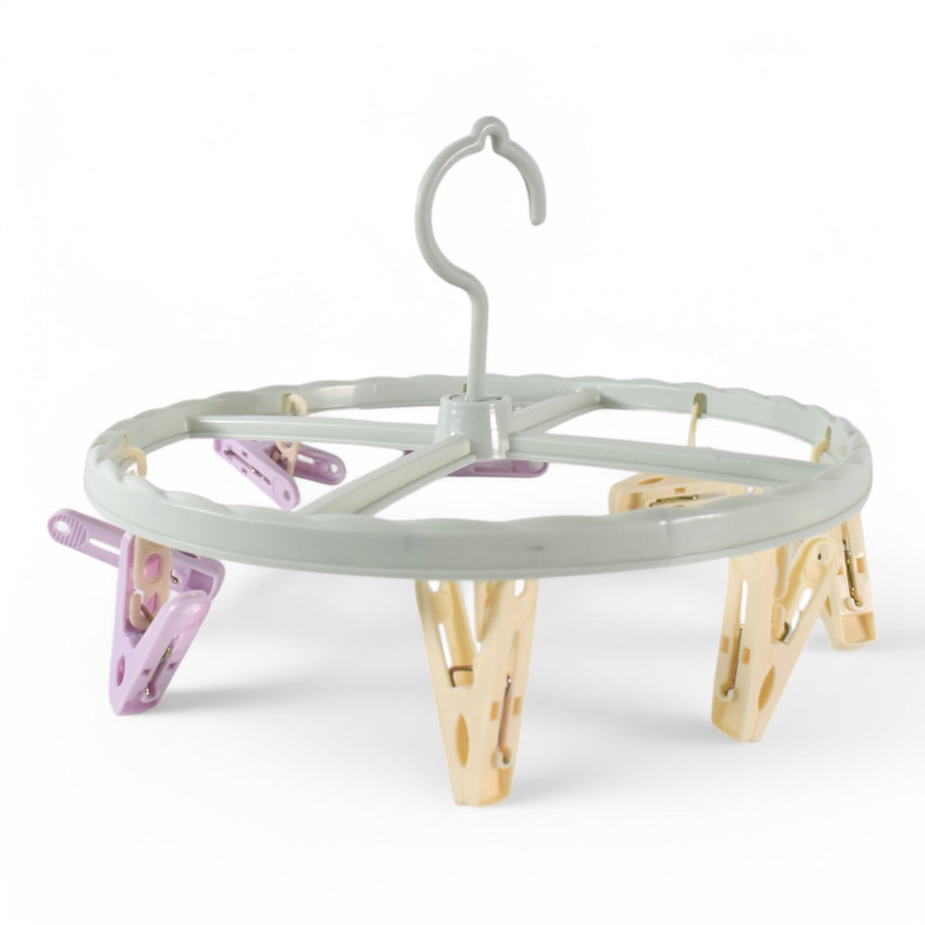 A light blue circular drying rack with purple and yellow clips is shown against a plain white background.