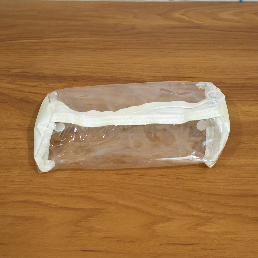 Empty clear PVC pencil case with white trim and zipper, centered on a light brown wooden surface.