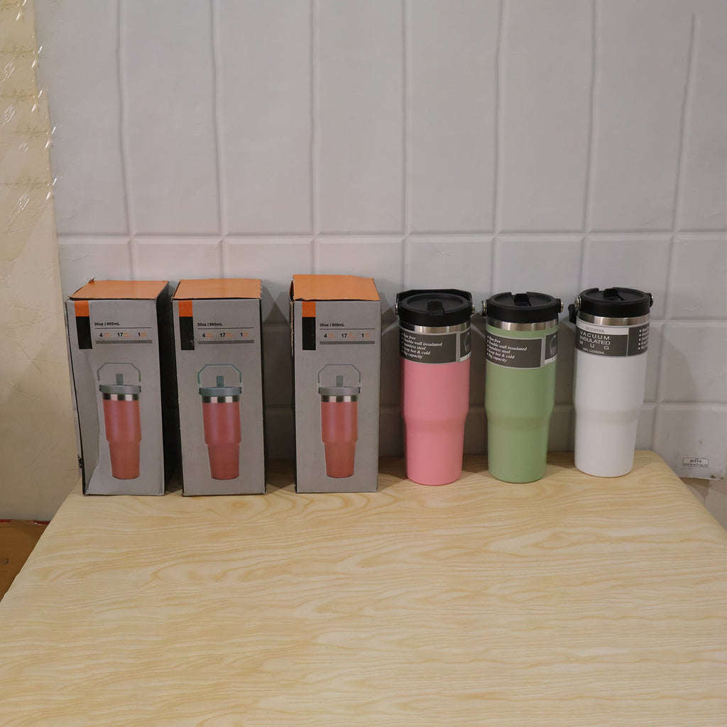 Three boxed pink tumblers and three unboxed tumblers in pink, green, and white sit on a wooden table.
