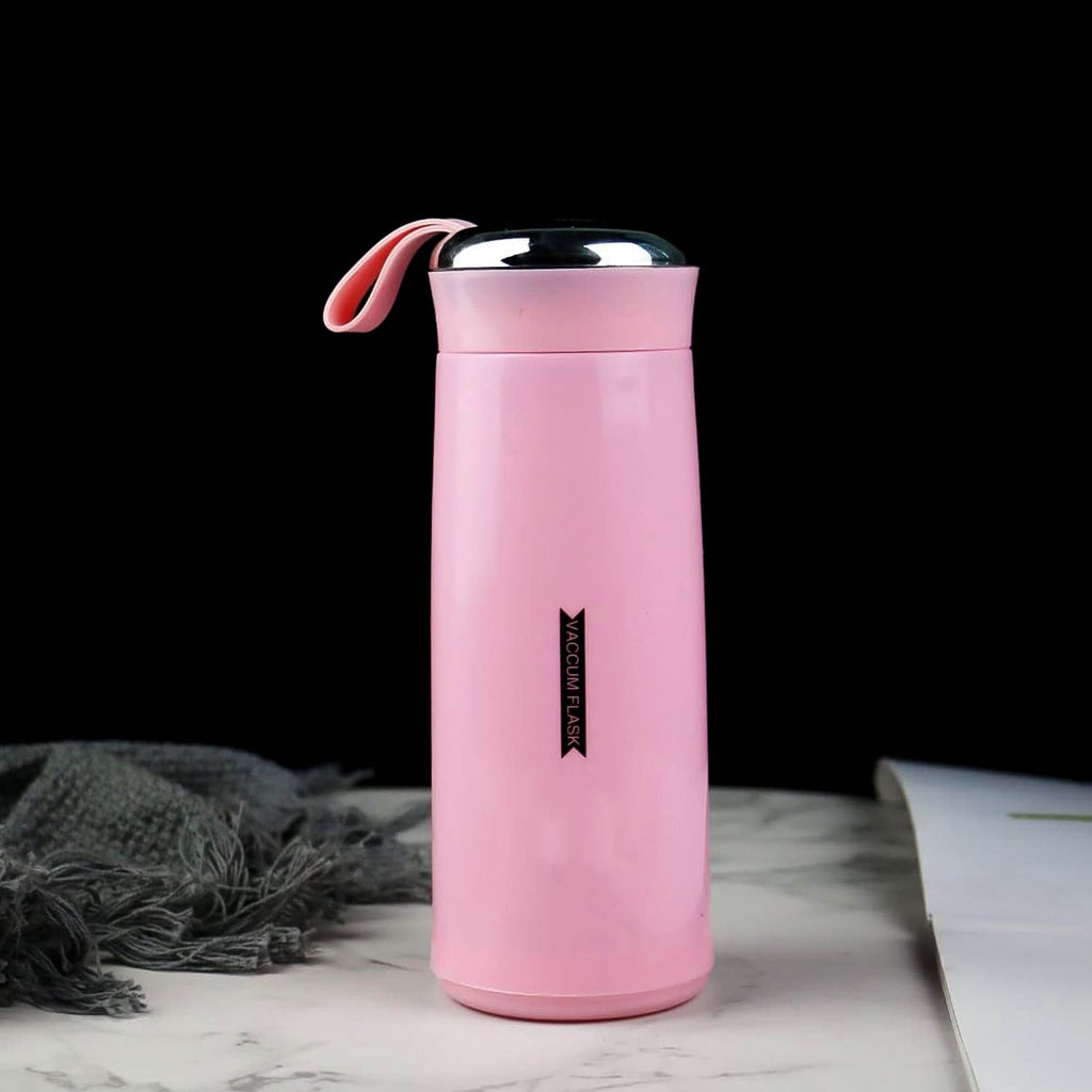 A pink vacuum flask with a silver lid and pink strap sits on a marble surface next to a grey cloth.