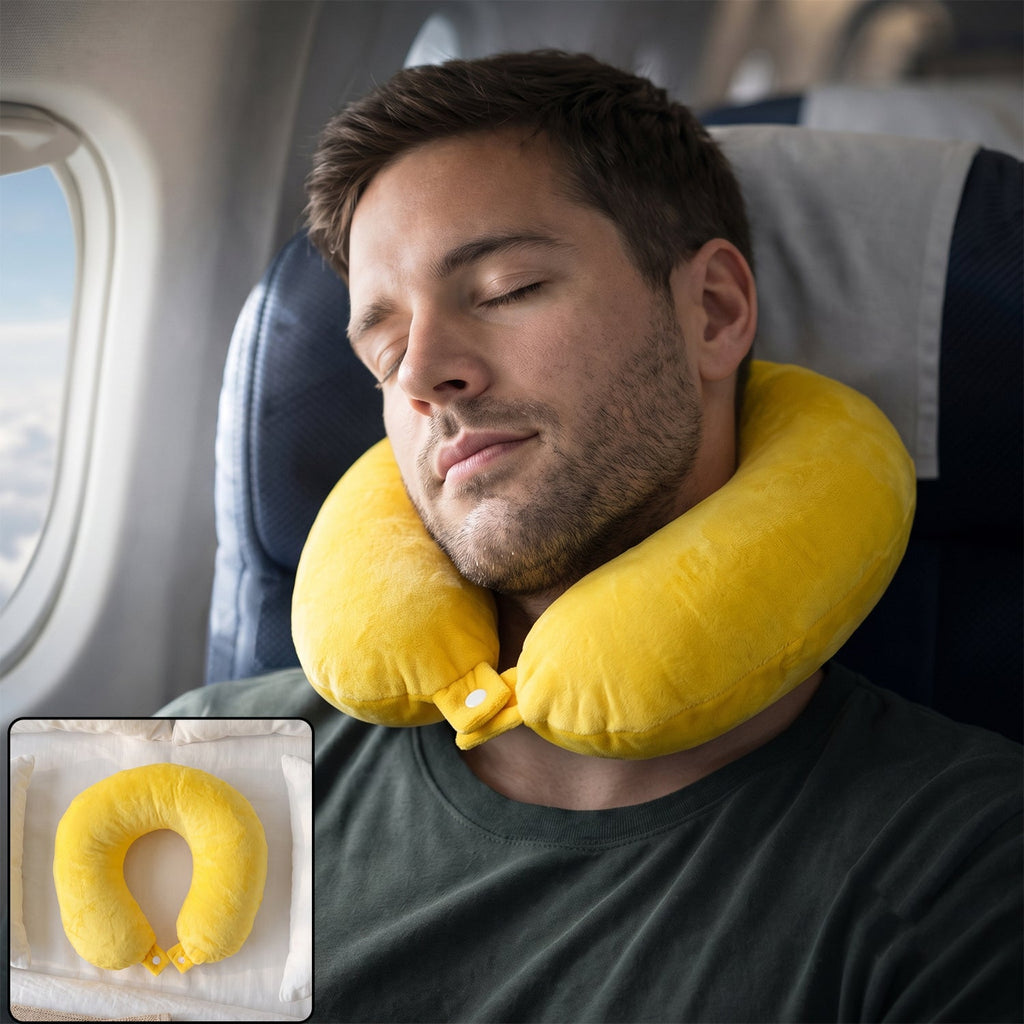 A man with a beard sleeps on an airplane, wearing a bright yellow U-shaped neck pillow with a white snap closure.
